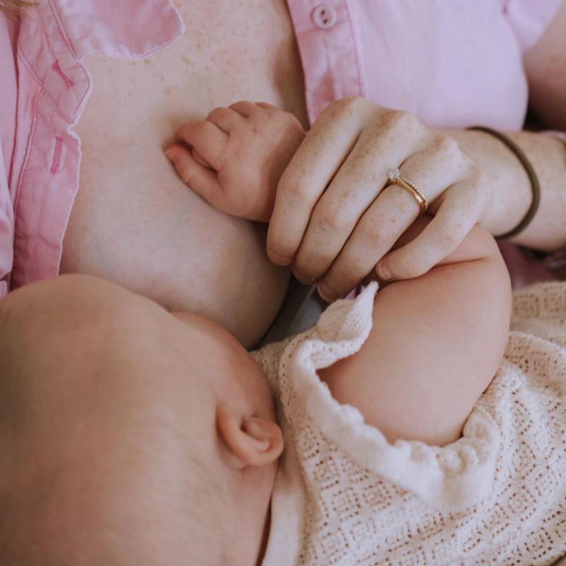 Close-up shot of a baby held by her mother while being breastfed
