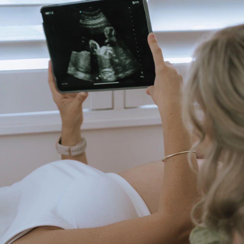 Close-up photo of a pregnant person holding a tablet showing an ultrasound image of their baby during a prenatal visit