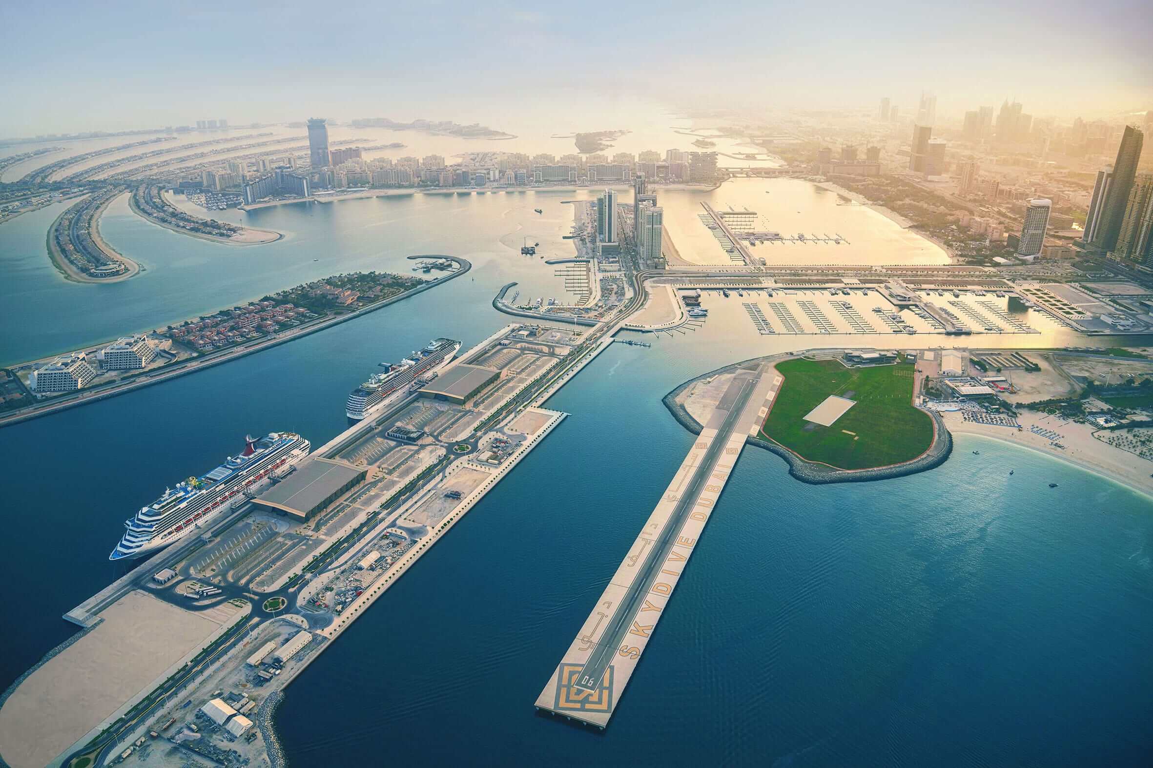 Aerial view of Dubai Marina with cruise ships docked and the Palm Jumeirah island in the background.