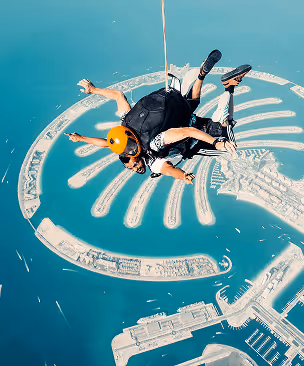 Two people tandem skydiving over a coastal area with distinctive palm-shaped islands.