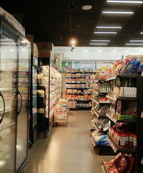 A grocery store aisle with shelves stocked with various packaged foods and refrigerated items.
