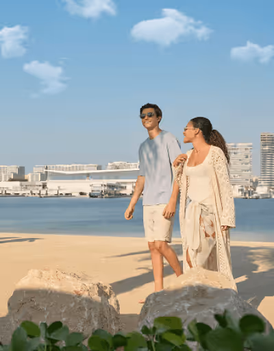 A man and woman walking on a beach.