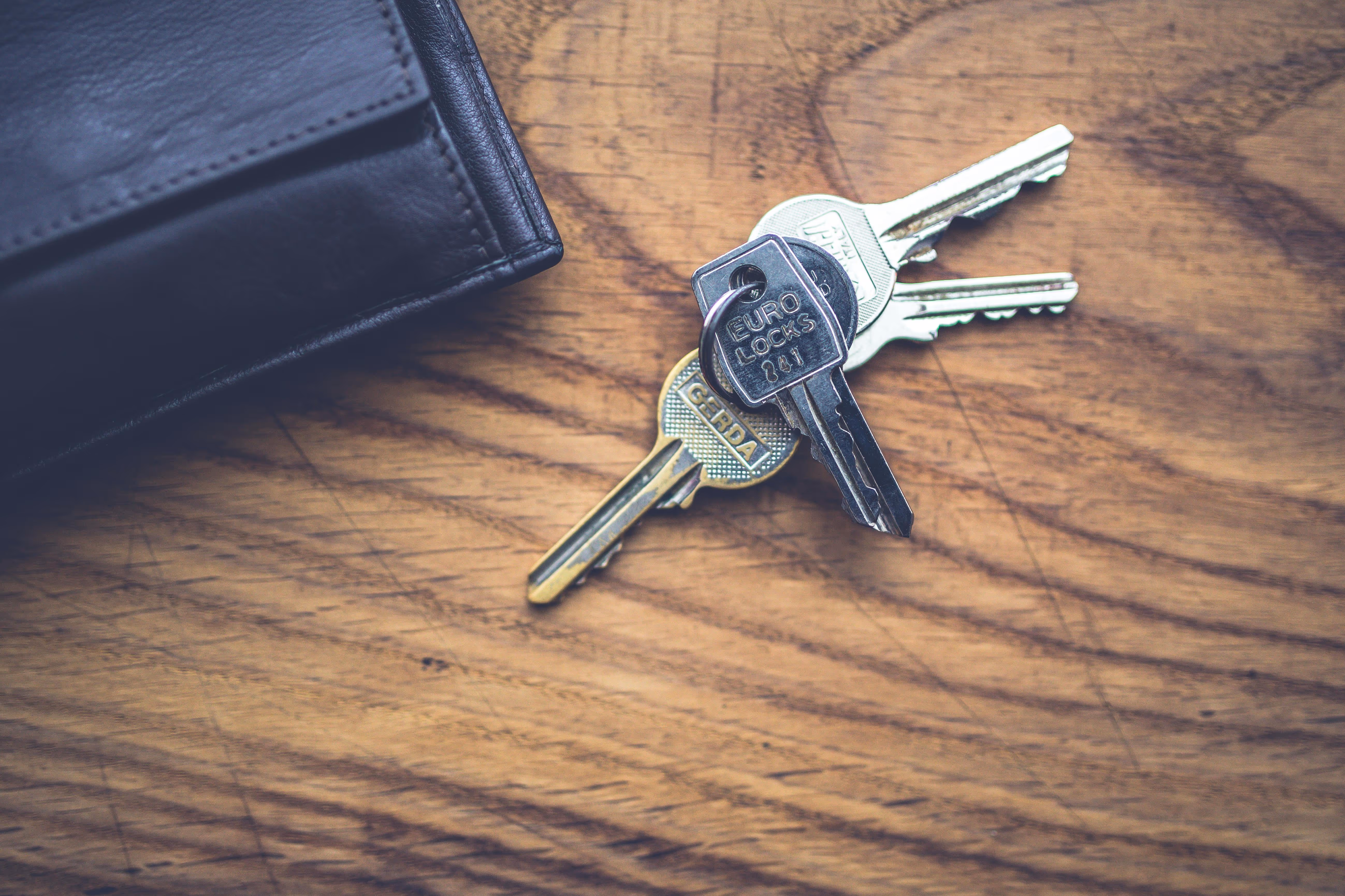 Close up image of pair of keys and wallet lay on the wooden table