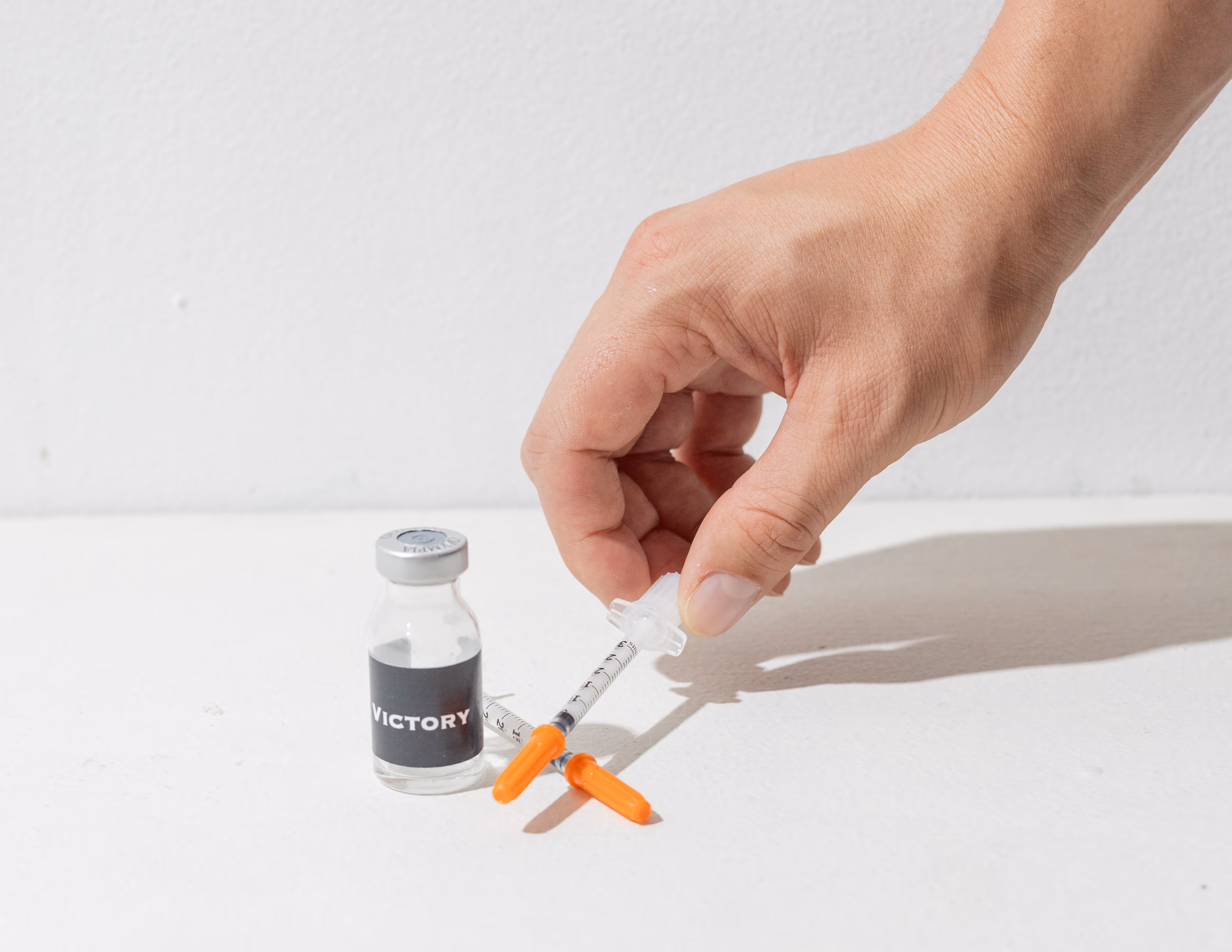 Hand holding syringe next to peptide vial showing proper peptide storage and handling for safe use and injection preparation | peptide storage and handling | Victory Men's Health