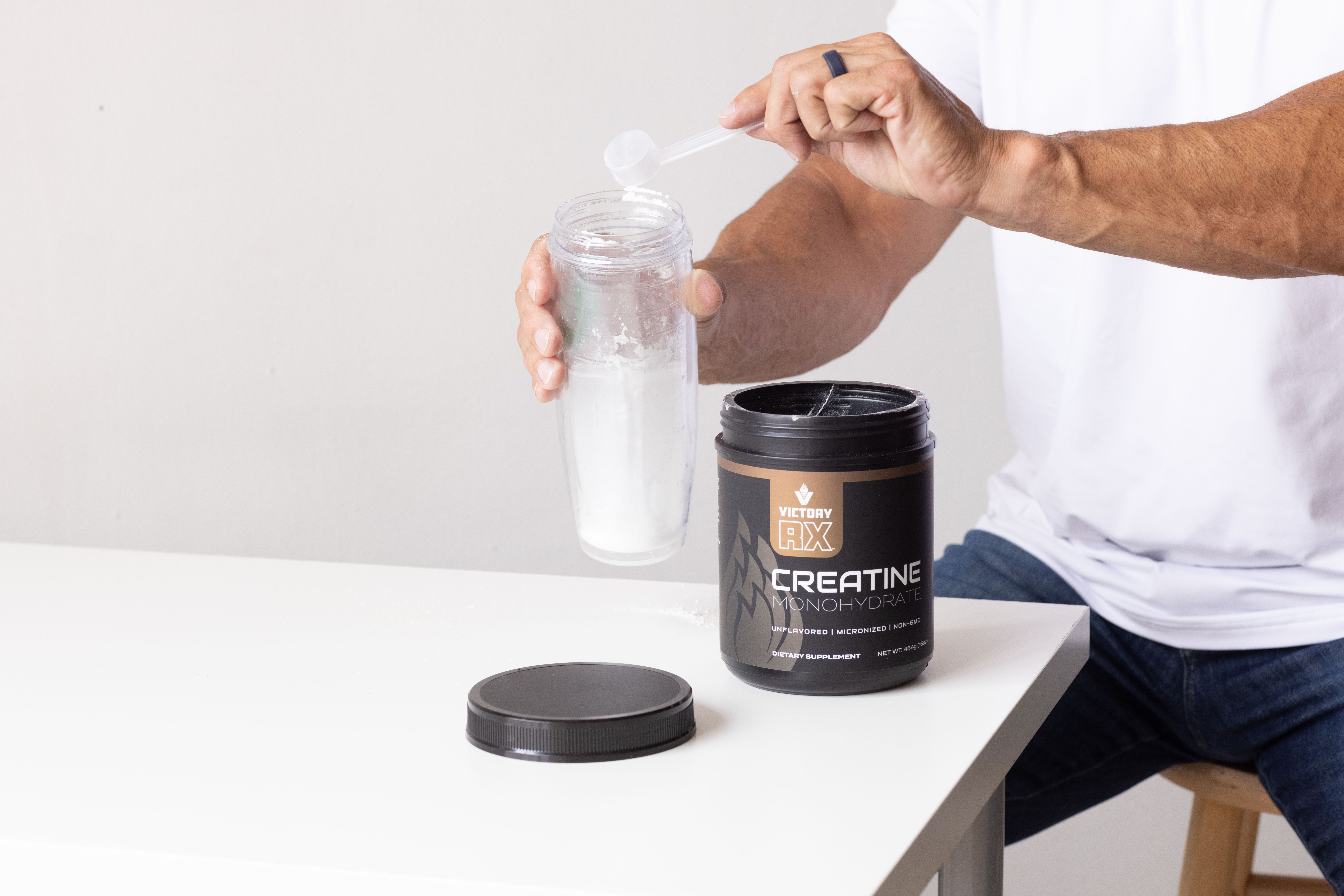 Man mixing Victory RX creatine monohydrate powder into a shaker bottle for cognitive and performance support.