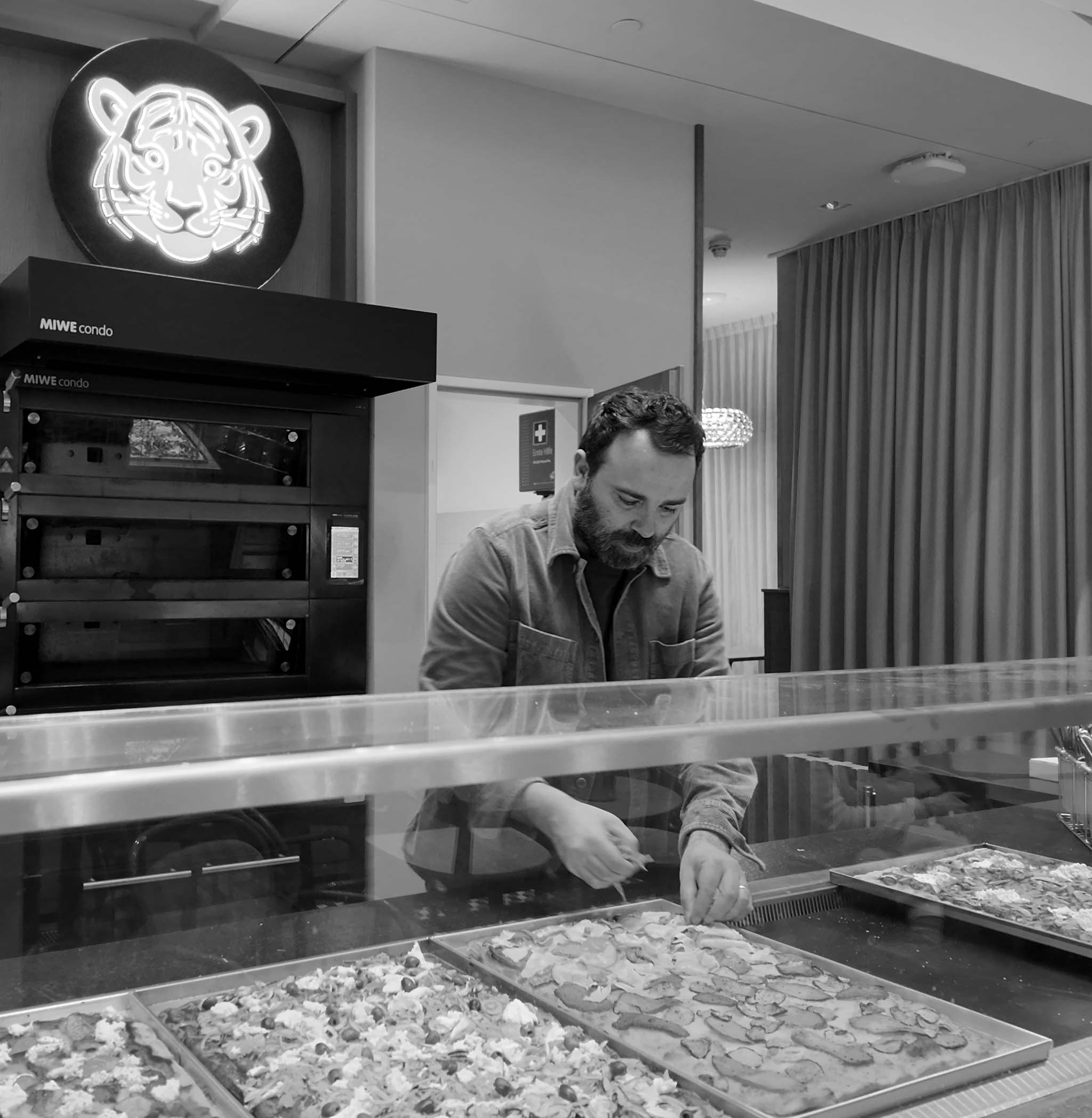 Chef placing cheese on raw pizza bread