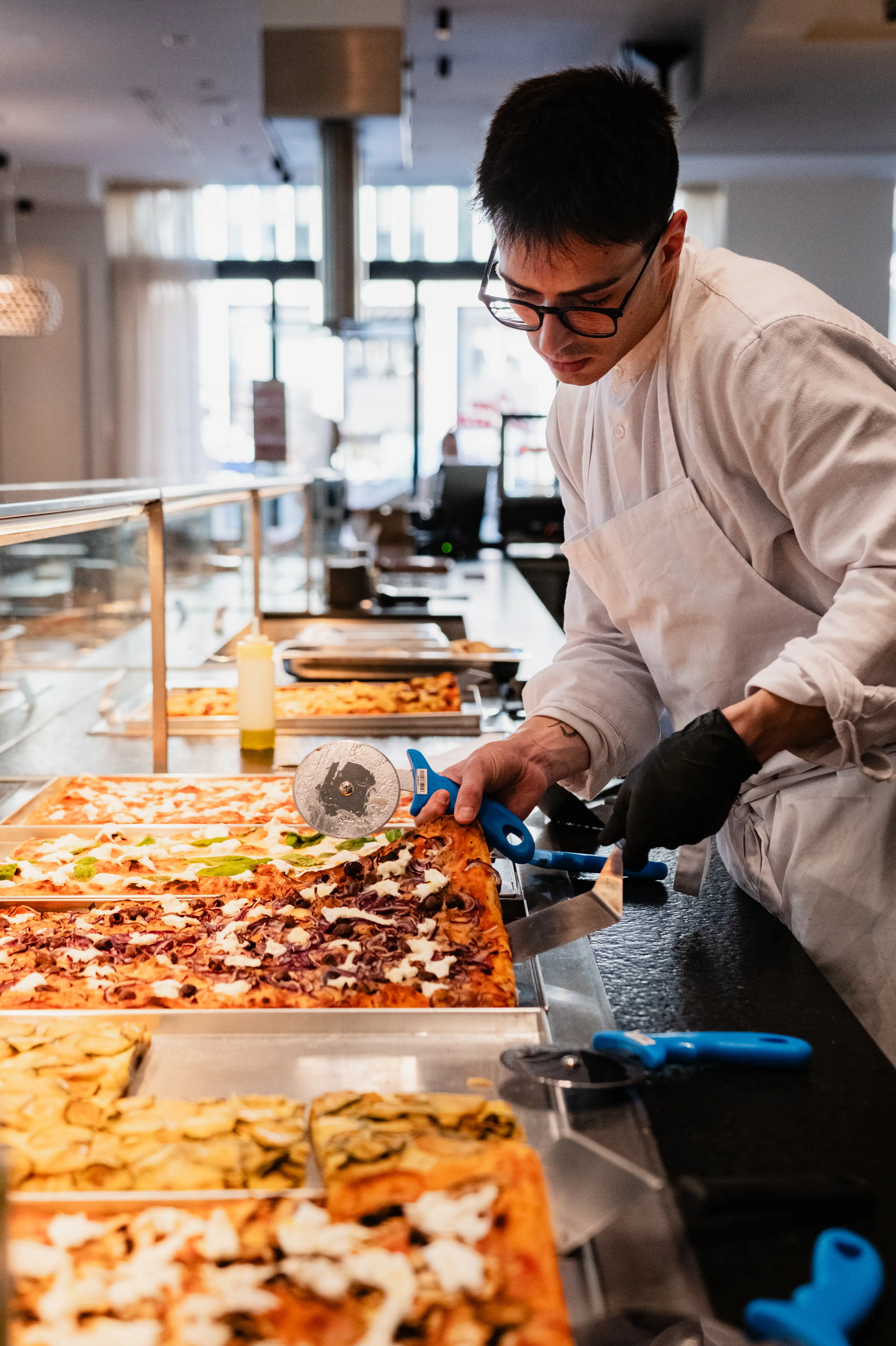 Chef placing cheese on raw pizza bread