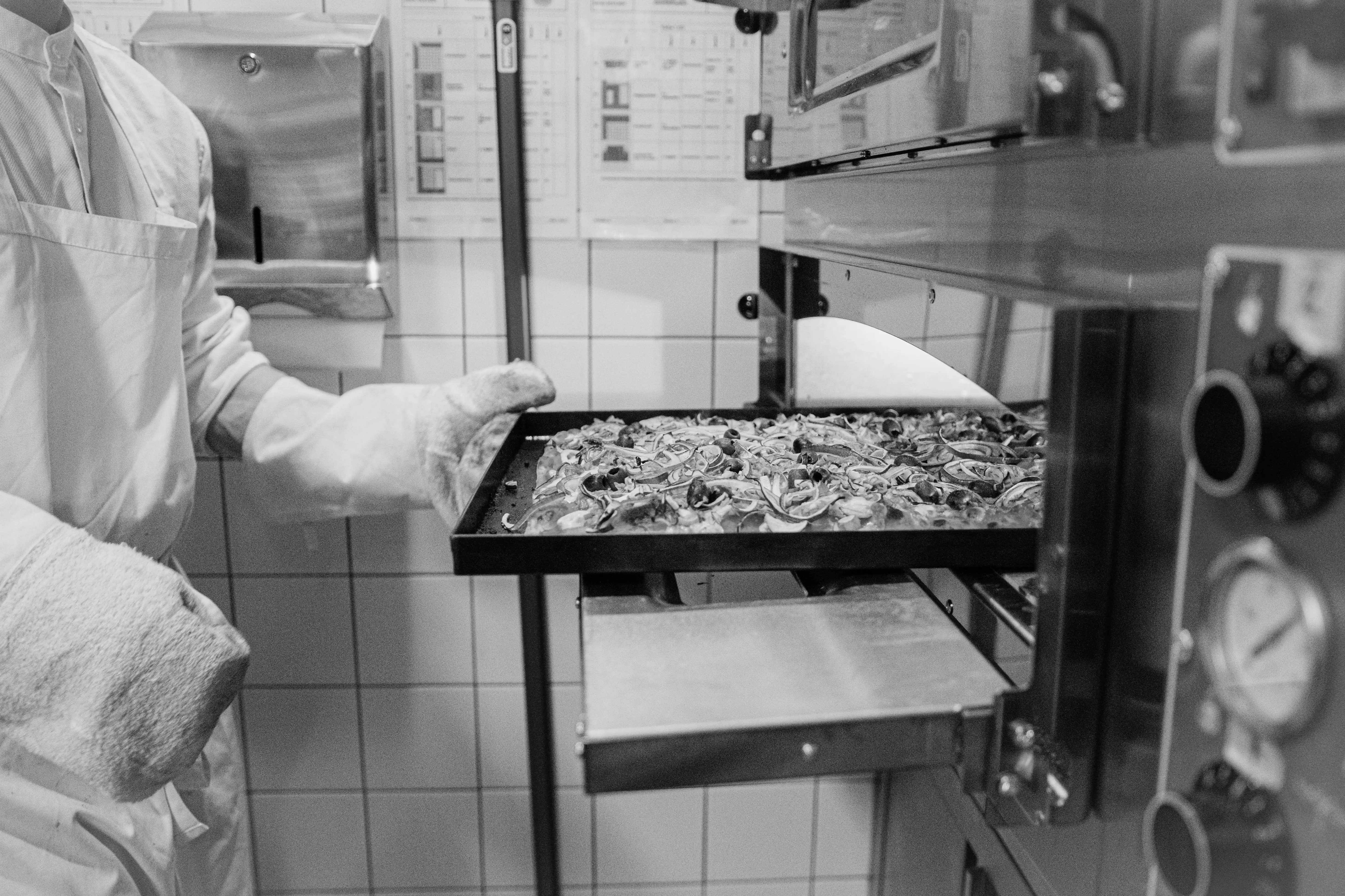 Two guys busy in the kitchen preparing pizza