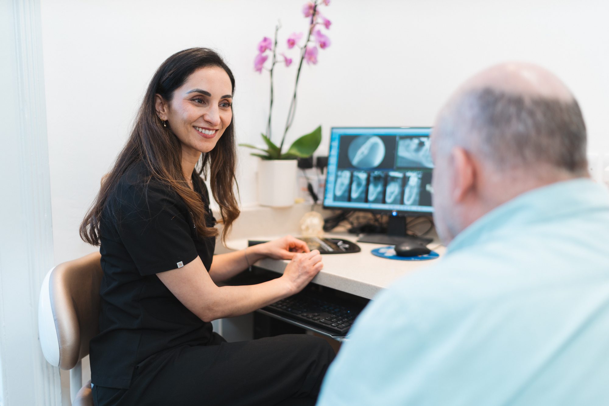 A smiling Waterfall dentist talking a patient through his scans in the Tooting practice