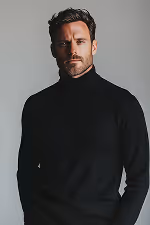 Portrait of a serious man with dark hair and beard wearing a black turtleneck sweater against a gray background.