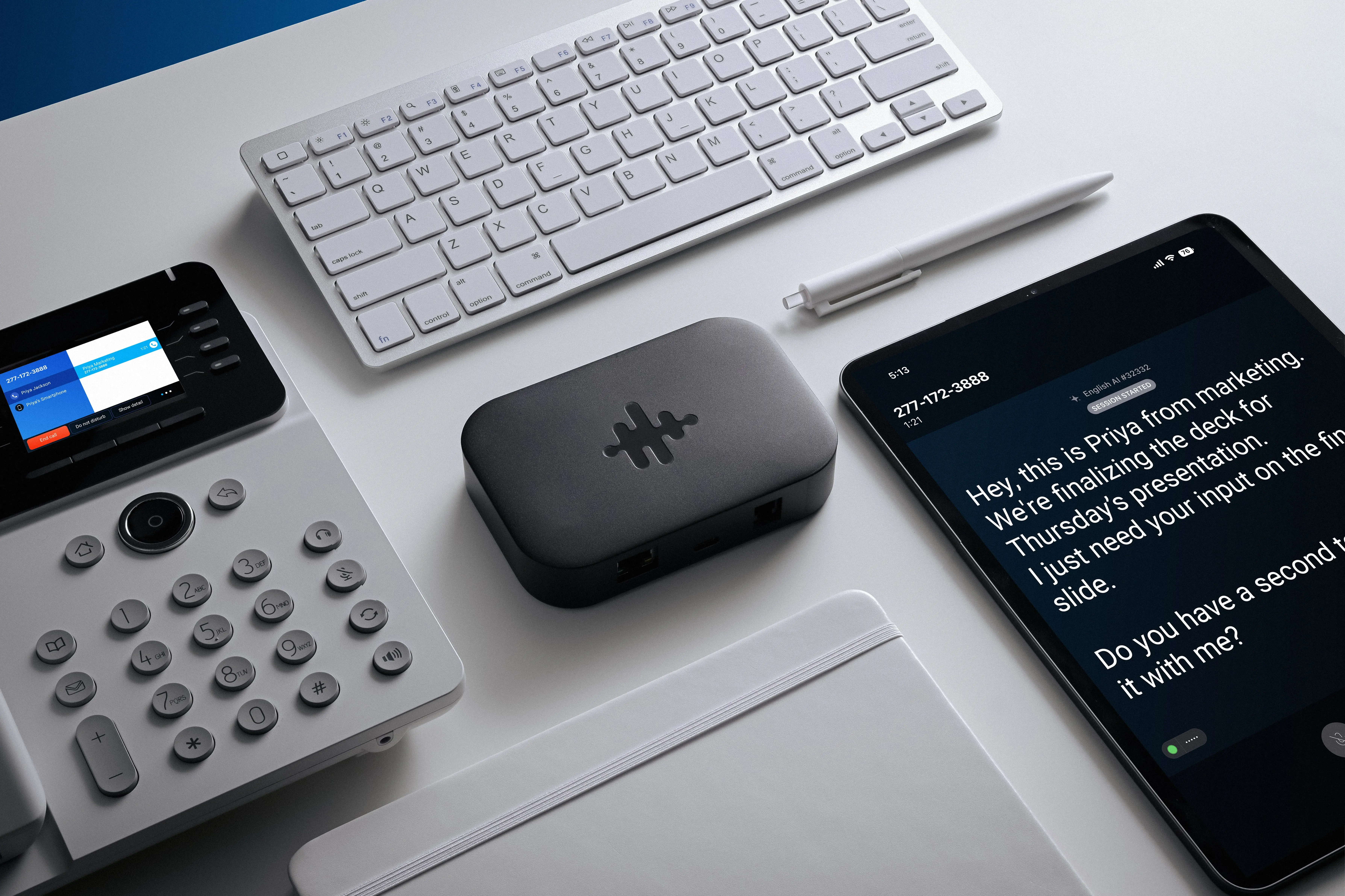 Bridge device on a desk alongside a desk phone and iPad showing captions