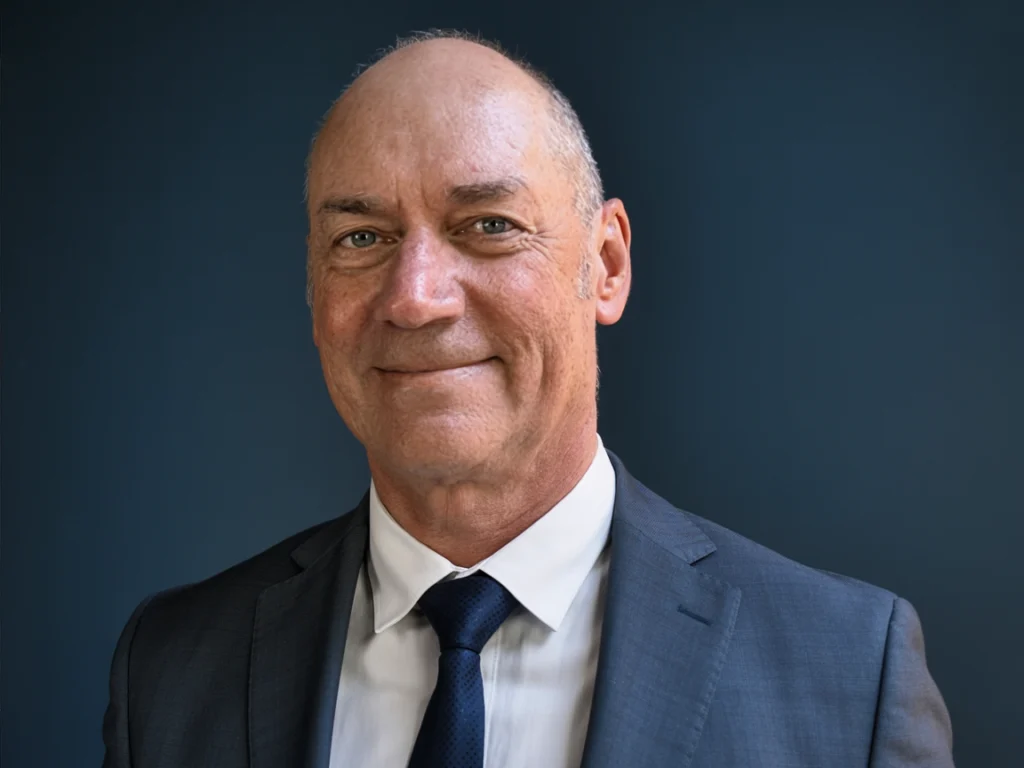 Dr. Scott Howell, Chief Commercial Officer, a smiling bald man in a blue suit, white shirt and navy tie