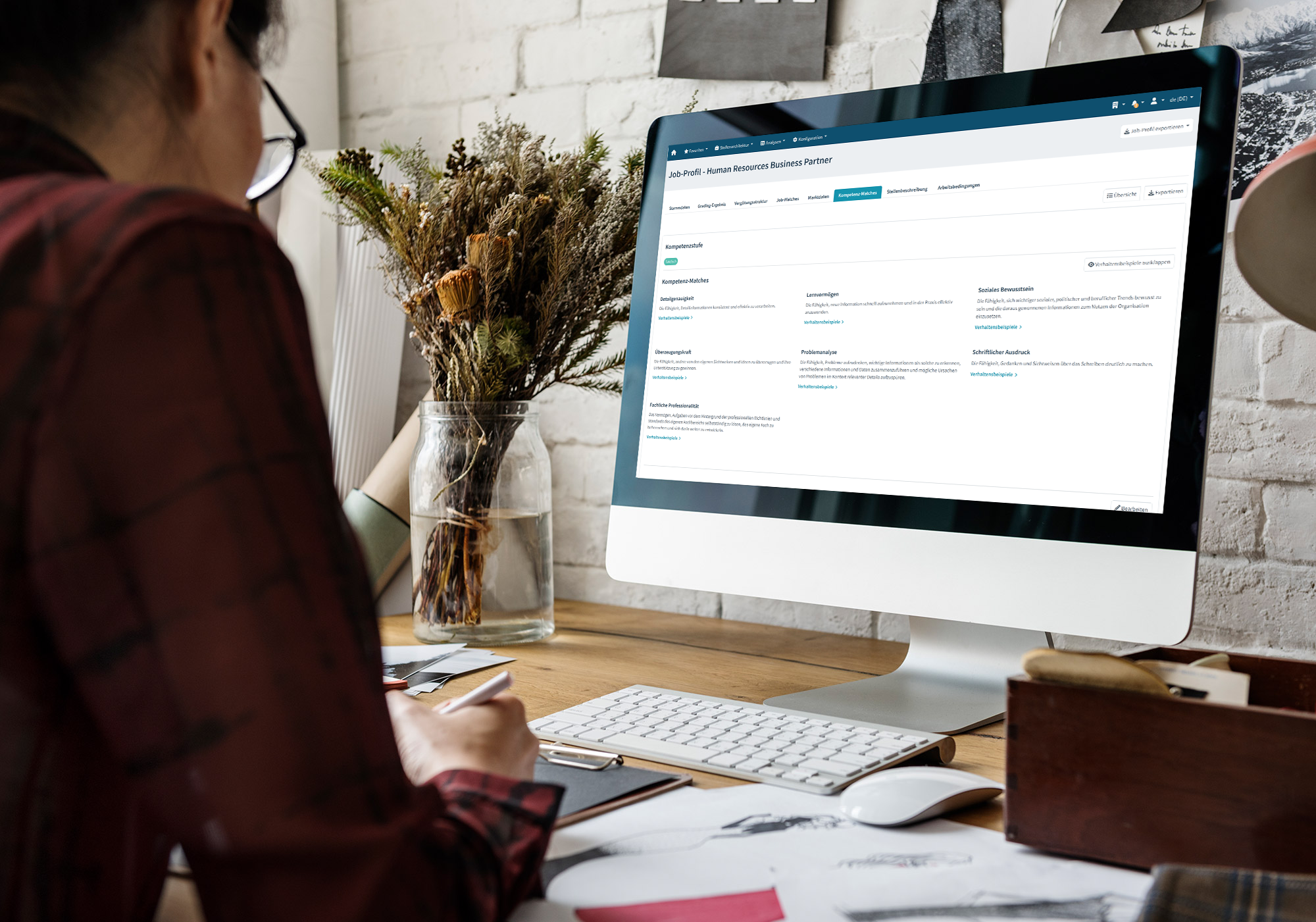 Mitarbeiter am Schreibtisch arbeitet am Computer mit geöffnetem Stellenprofil als HR Business Partner