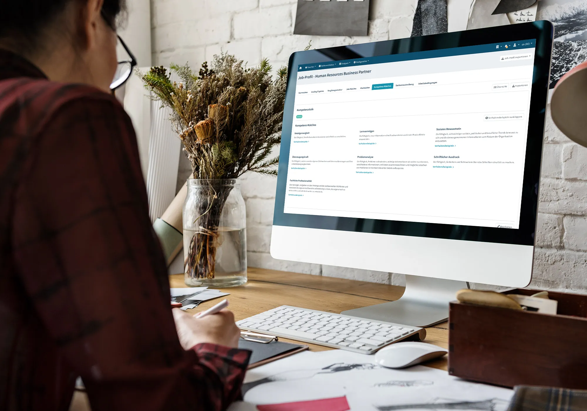 Mitarbeiter am Schreibtisch arbeitet am Computer mit geöffnetem Stellenprofil als HR Business Partner