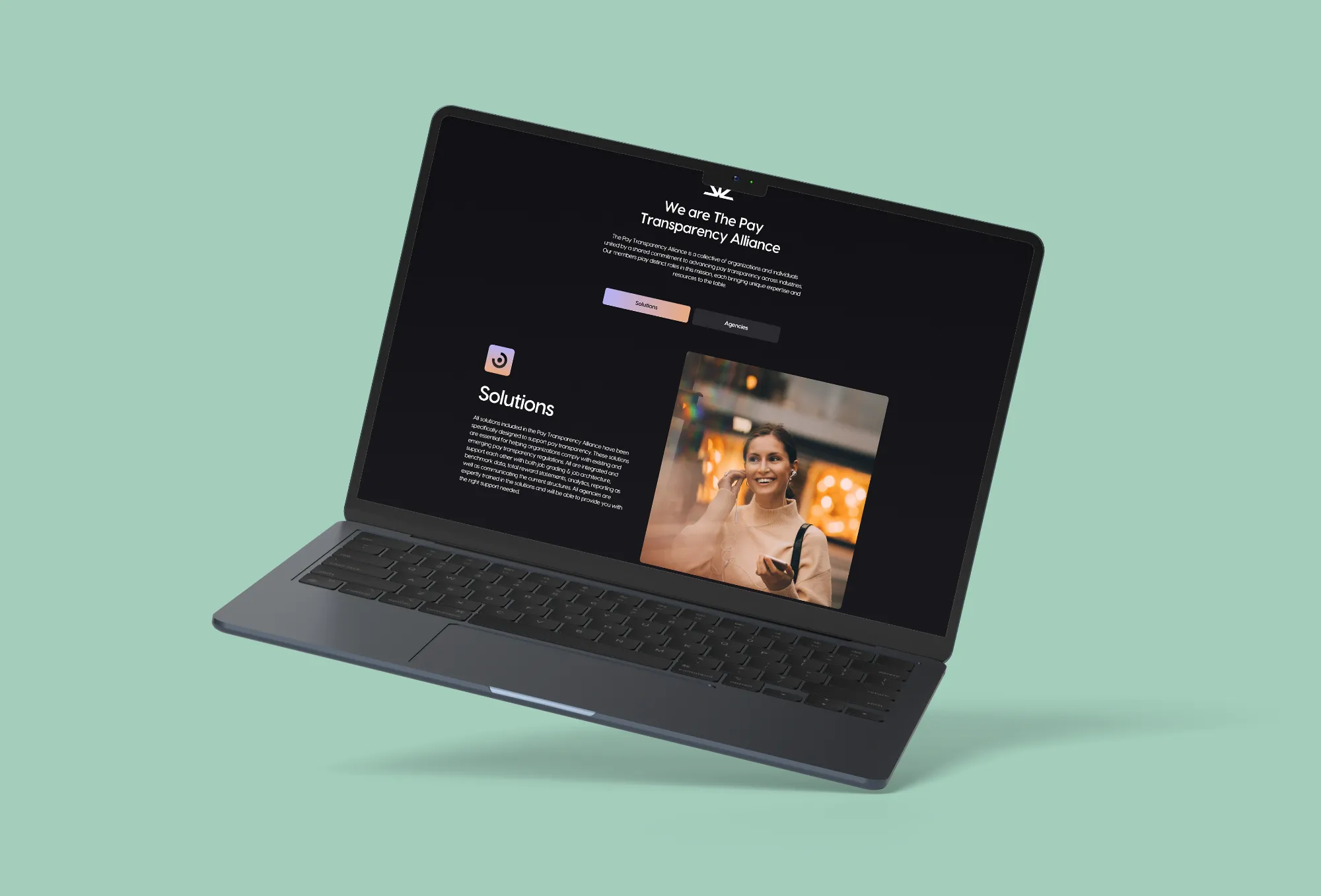 Laptop screen showing The Pay Transparency Alliance website with Solutions section and a woman listening to earphones.