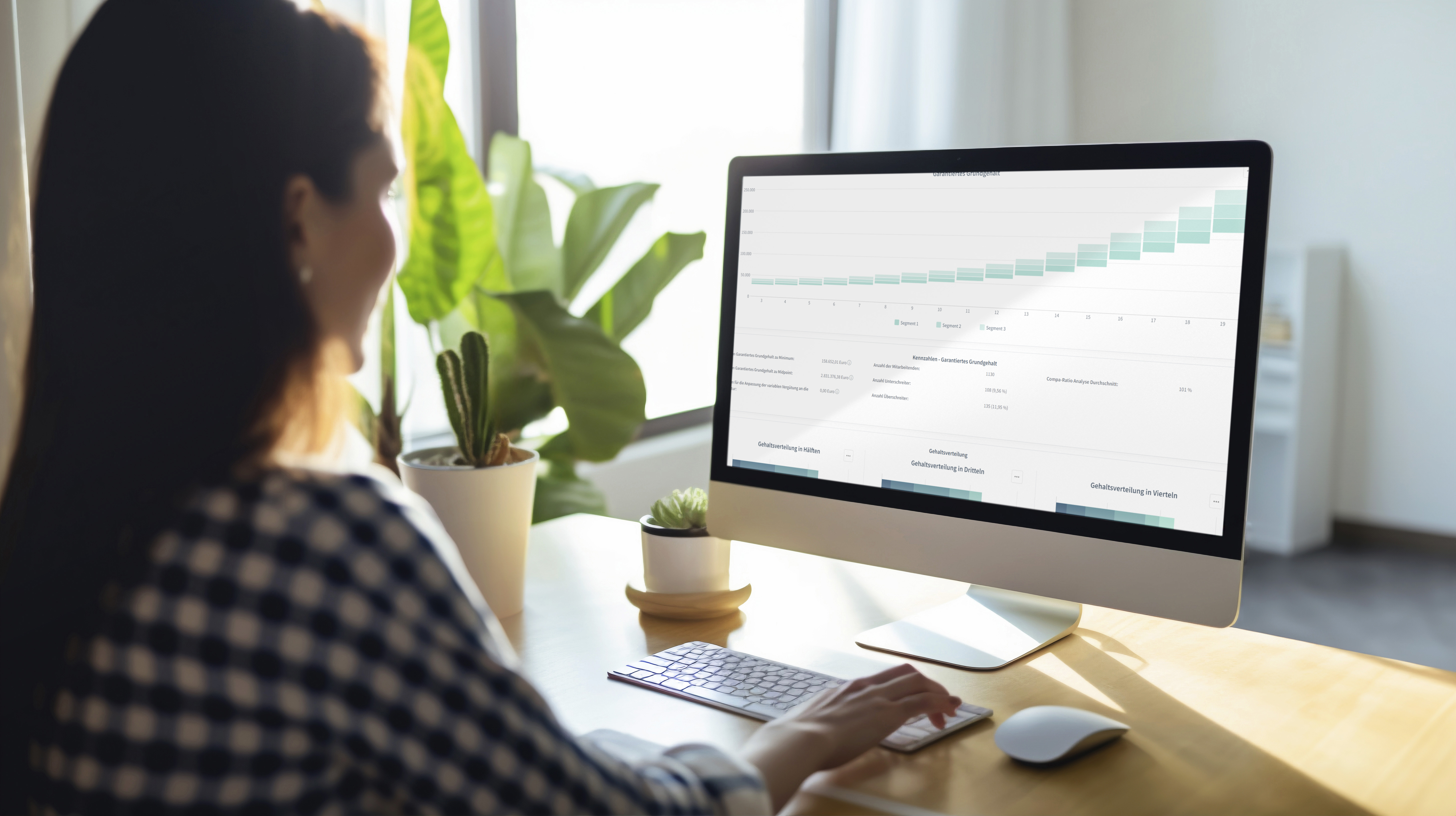 Frau analysiert Diagramme und Daten-Dashboards am Desktop-Computer in einem hellen Büro