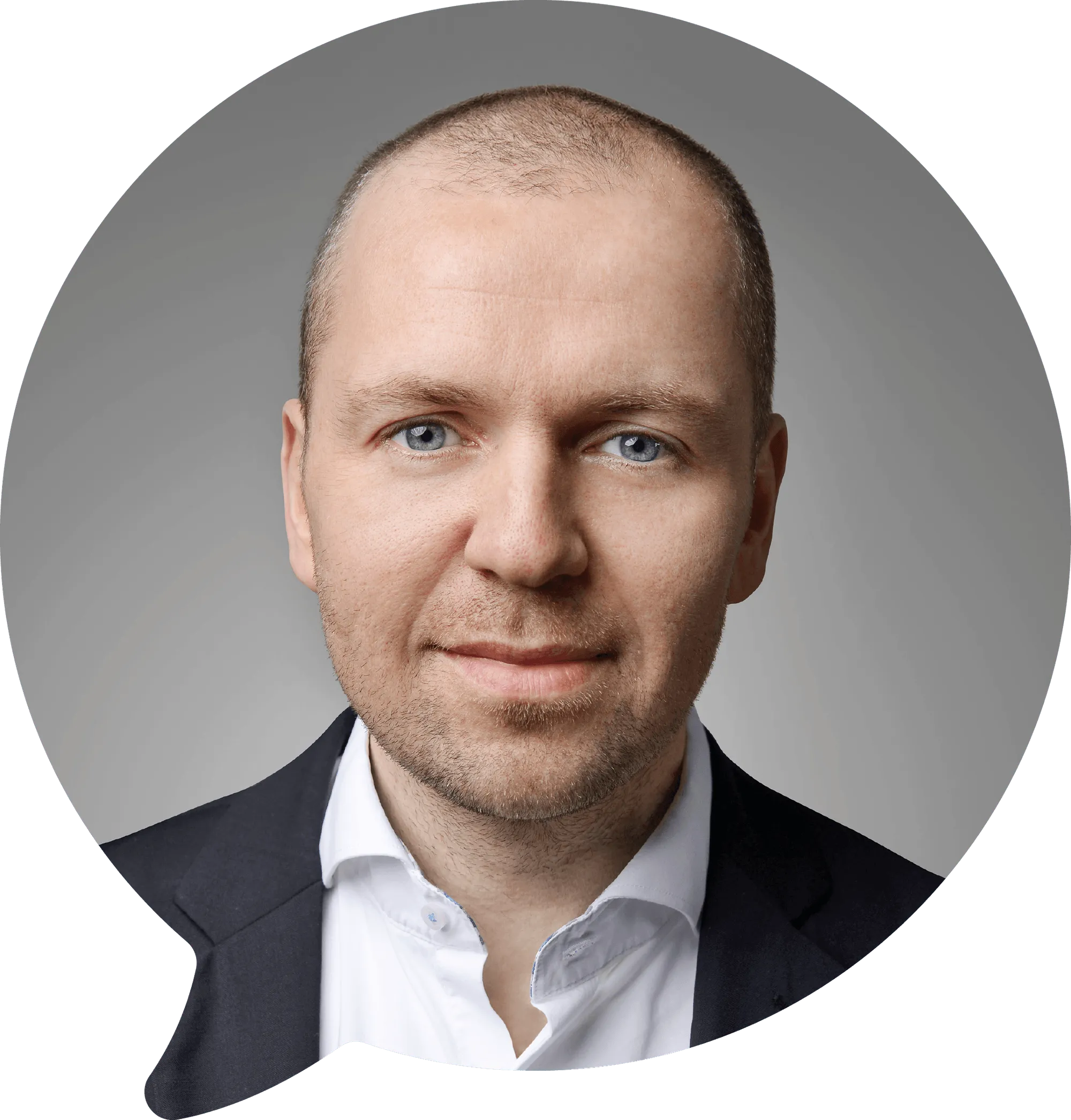Porträt eines lächelnden Mannes mit kurzen, dünnen Haaren, blauen Augen, weißem Hemd und dunklem Sakko vor grauem Hintergrund.