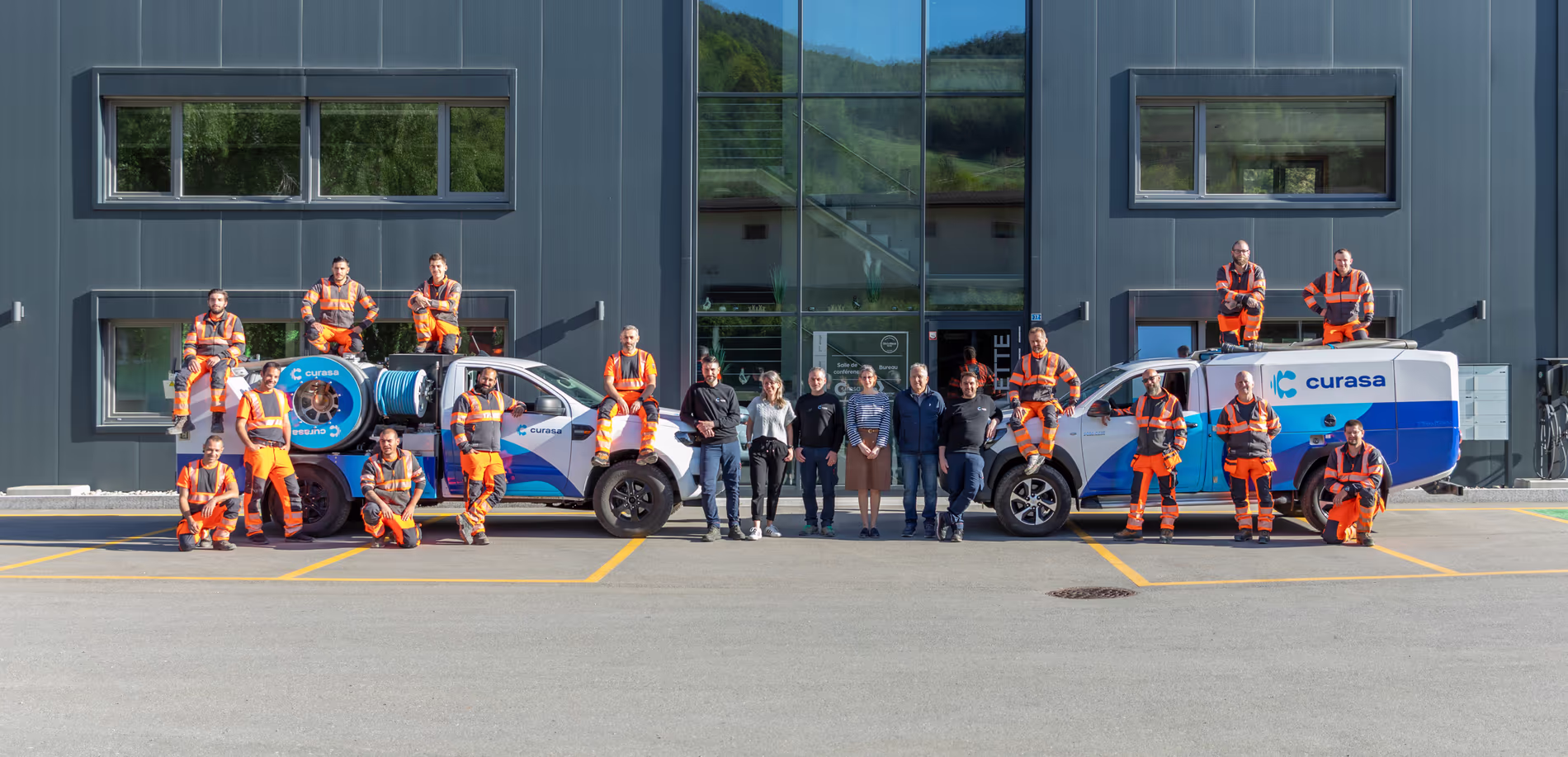 20 employés de Curasa pose devant et sur deux camionnette d'intervention
