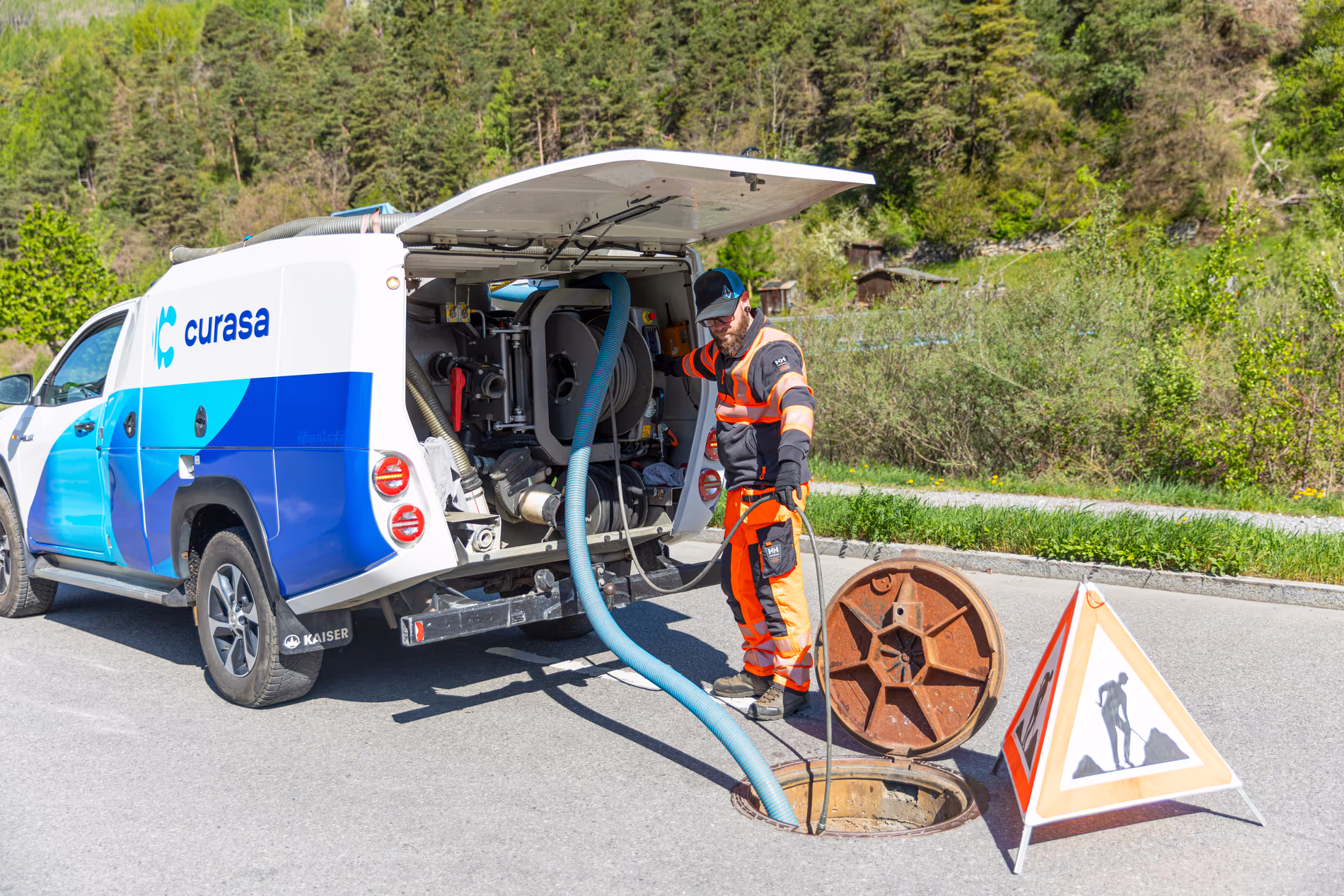 Un employé fait descendre des tubes depuis sa camionnette dans une bouche d'égout sur la route
