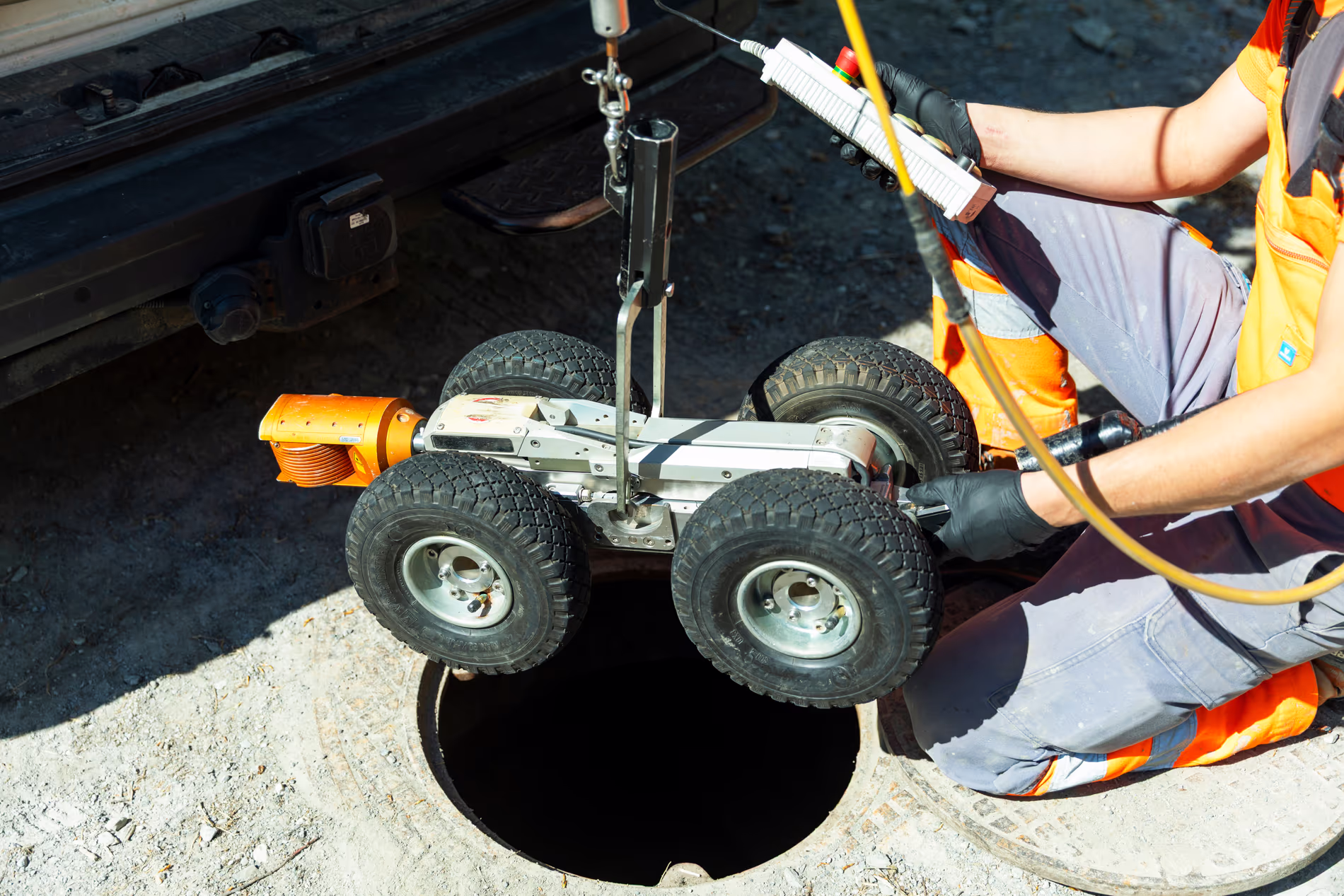 Un employé fait descendre un robot-caméra dans une bouche d'égout.