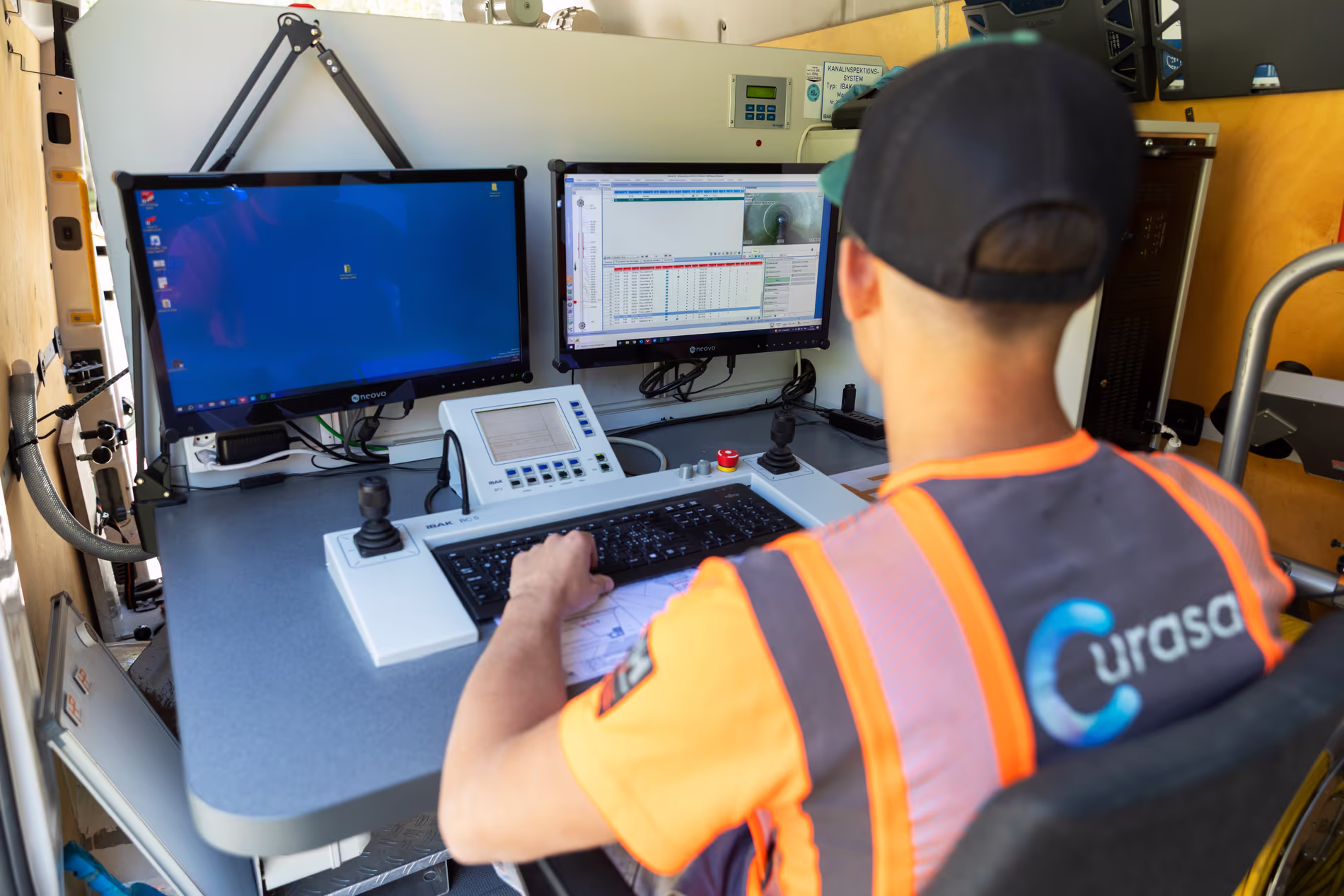 Un employé est à son poste dans une camionnette et analyse les résultats d'une inspection de canalisation.
