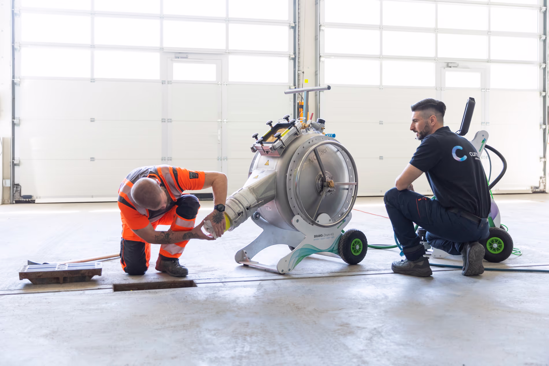 Deux employé sont en train de travailler sur une machine qui permet de chemiser les canalisations.