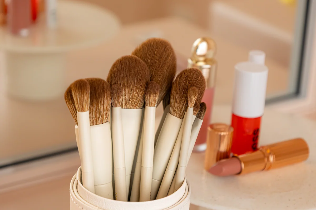 Three women smiling closely together with pink eye makeup and orchid flowers on skin and shoulder.