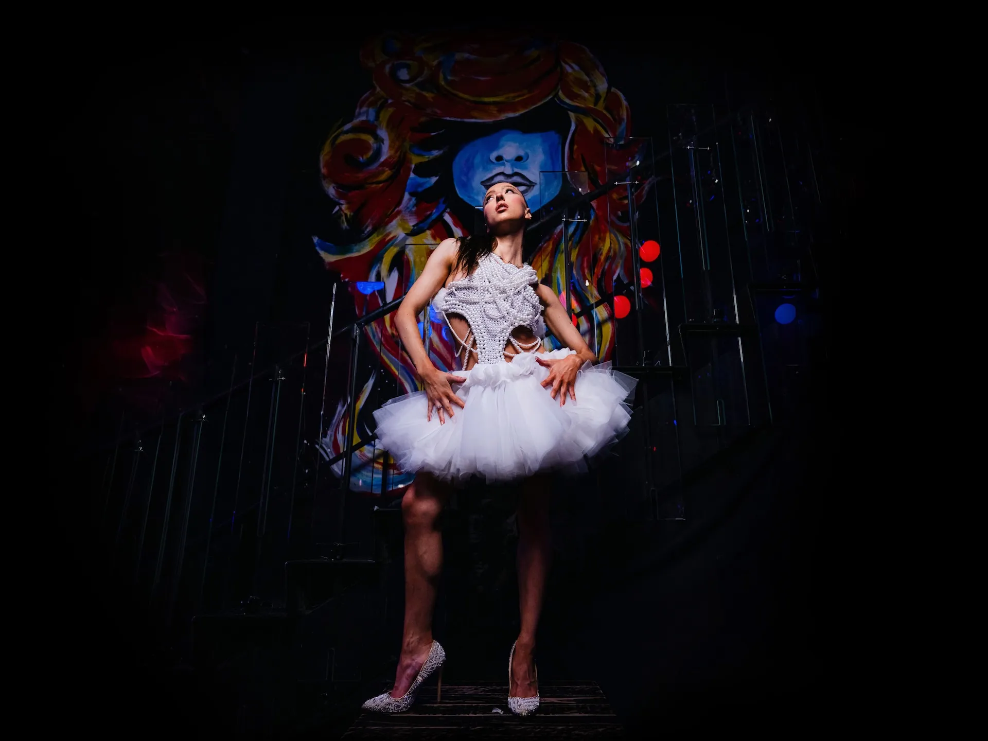 Woman in a sheer white top taking a photo with a camera near the Colosseum at sunset.