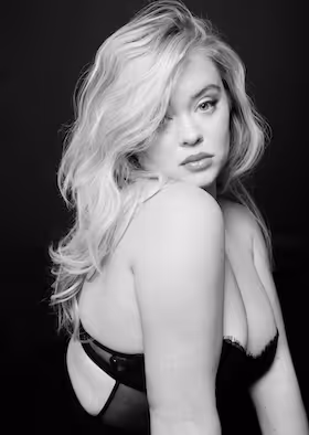 Black and white portrait of a woman with long wavy hair looking over her shoulder.