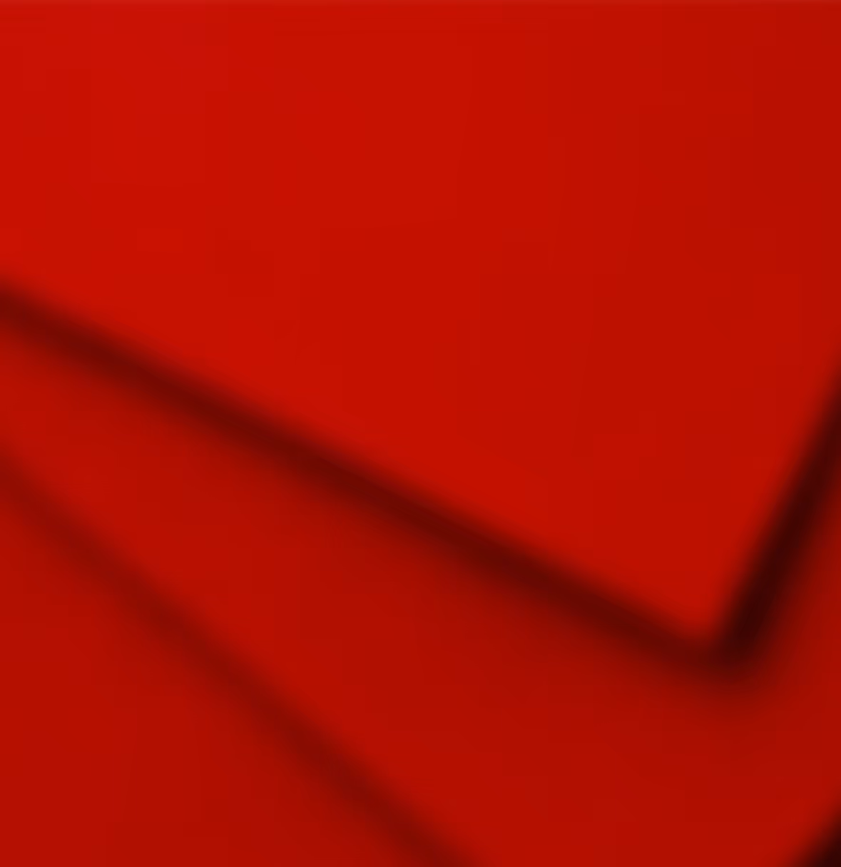 Close-up of smooth, folded red fabric with shadows creating depth and texture.