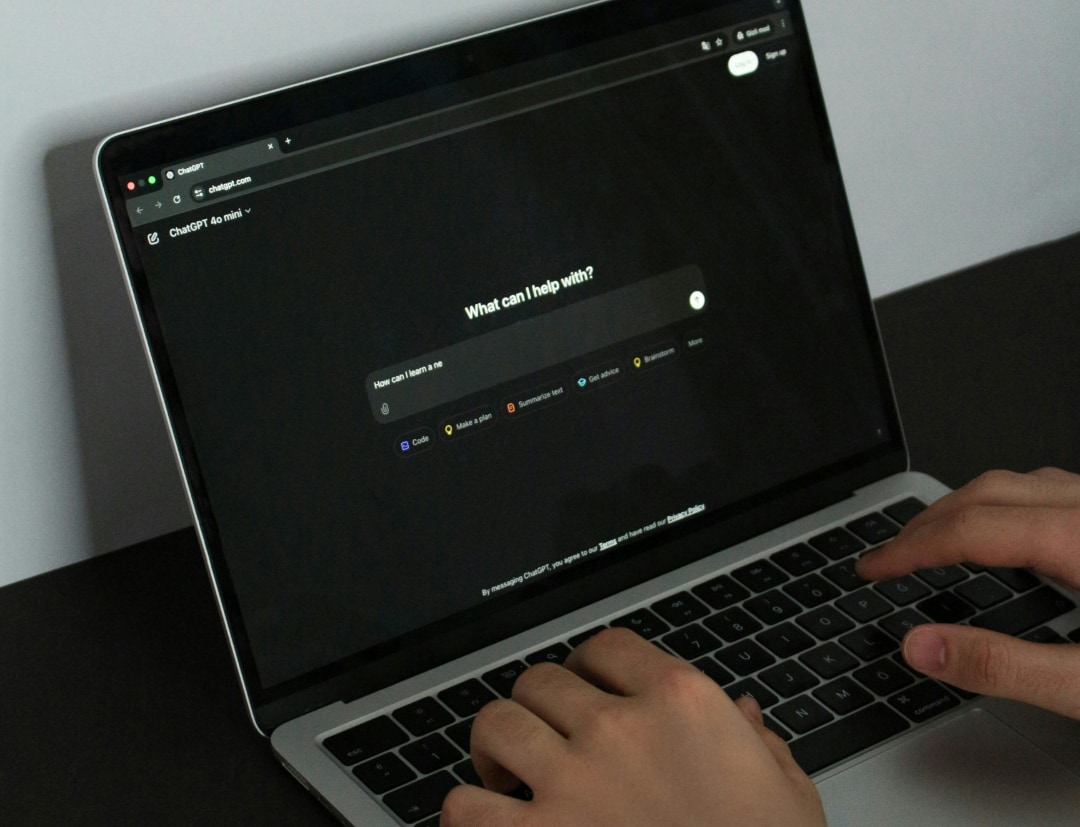 Hands typing on a laptop with ChatGPT open at the What can I help with prompt.