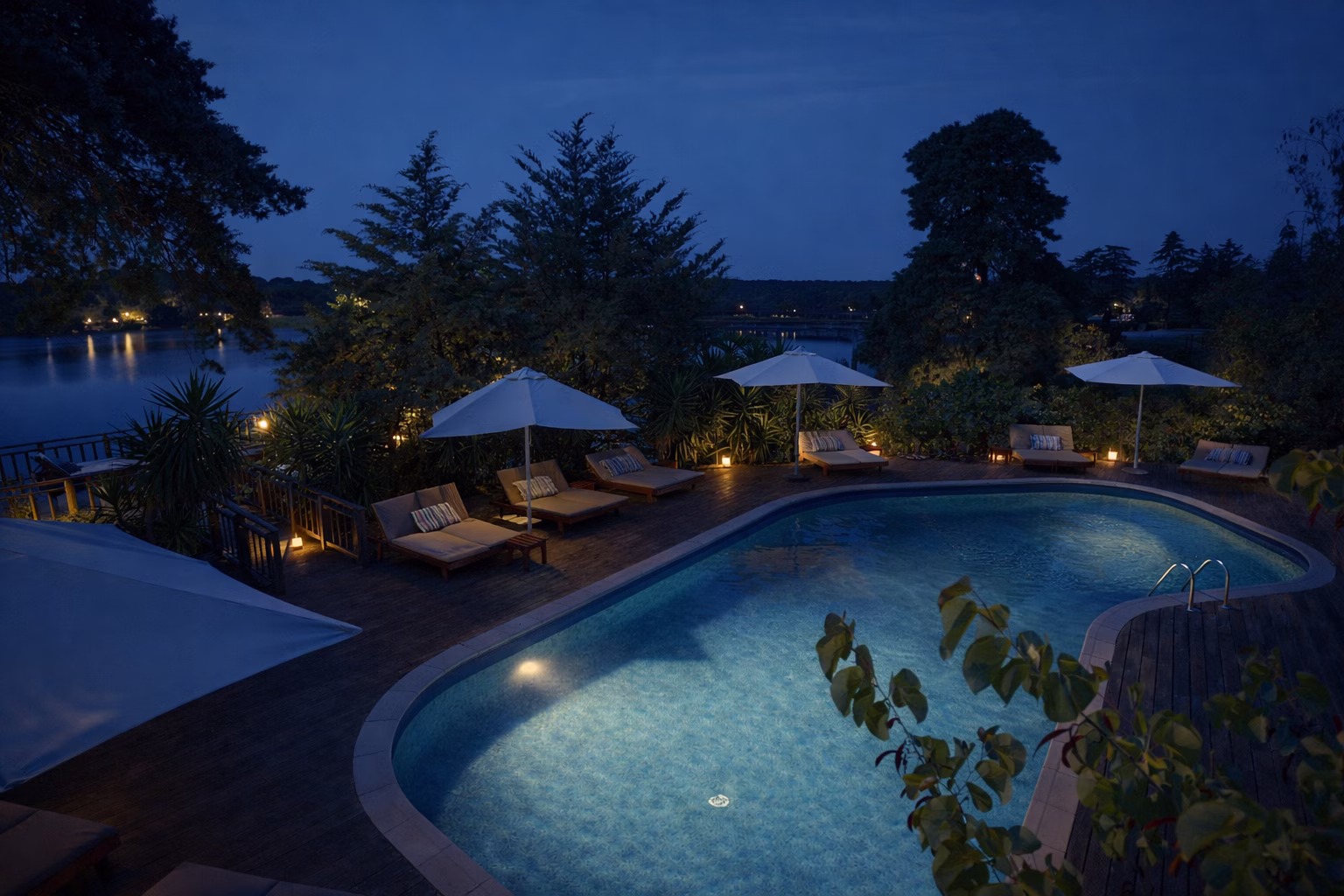 Hotel Vale do Gaio's outdoor pool at dusk, lit from below, with sun loungers and parasols beside the lake