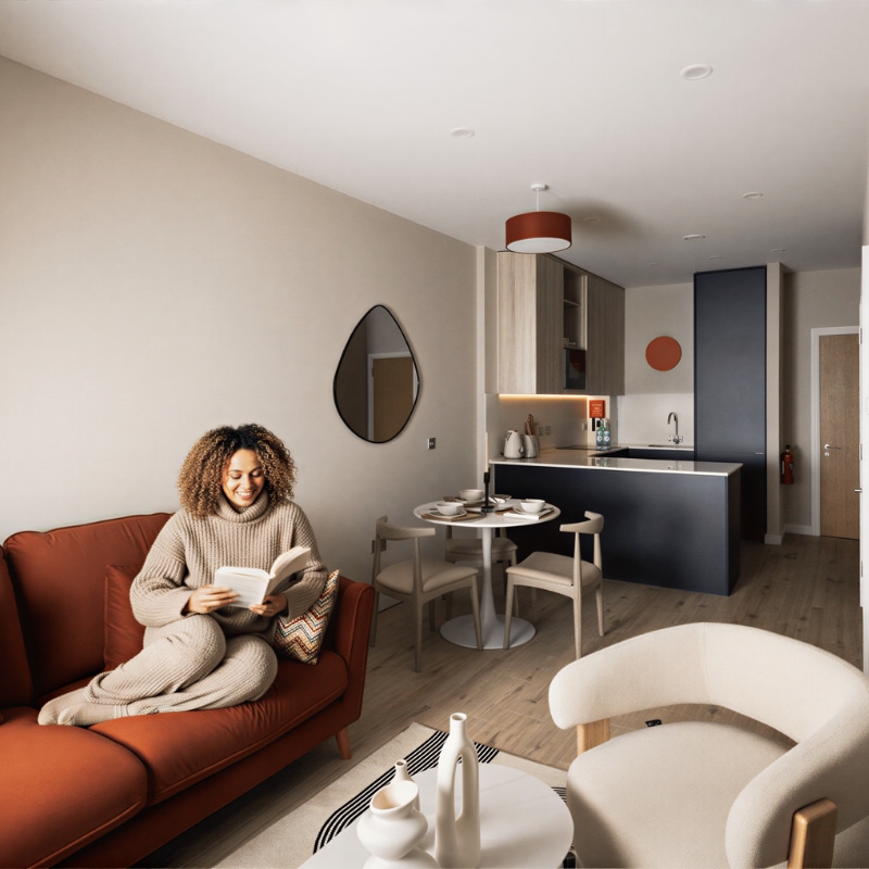 Apartment at Sand House with a resident reading on a rust coloured sofa beside the open kitchen