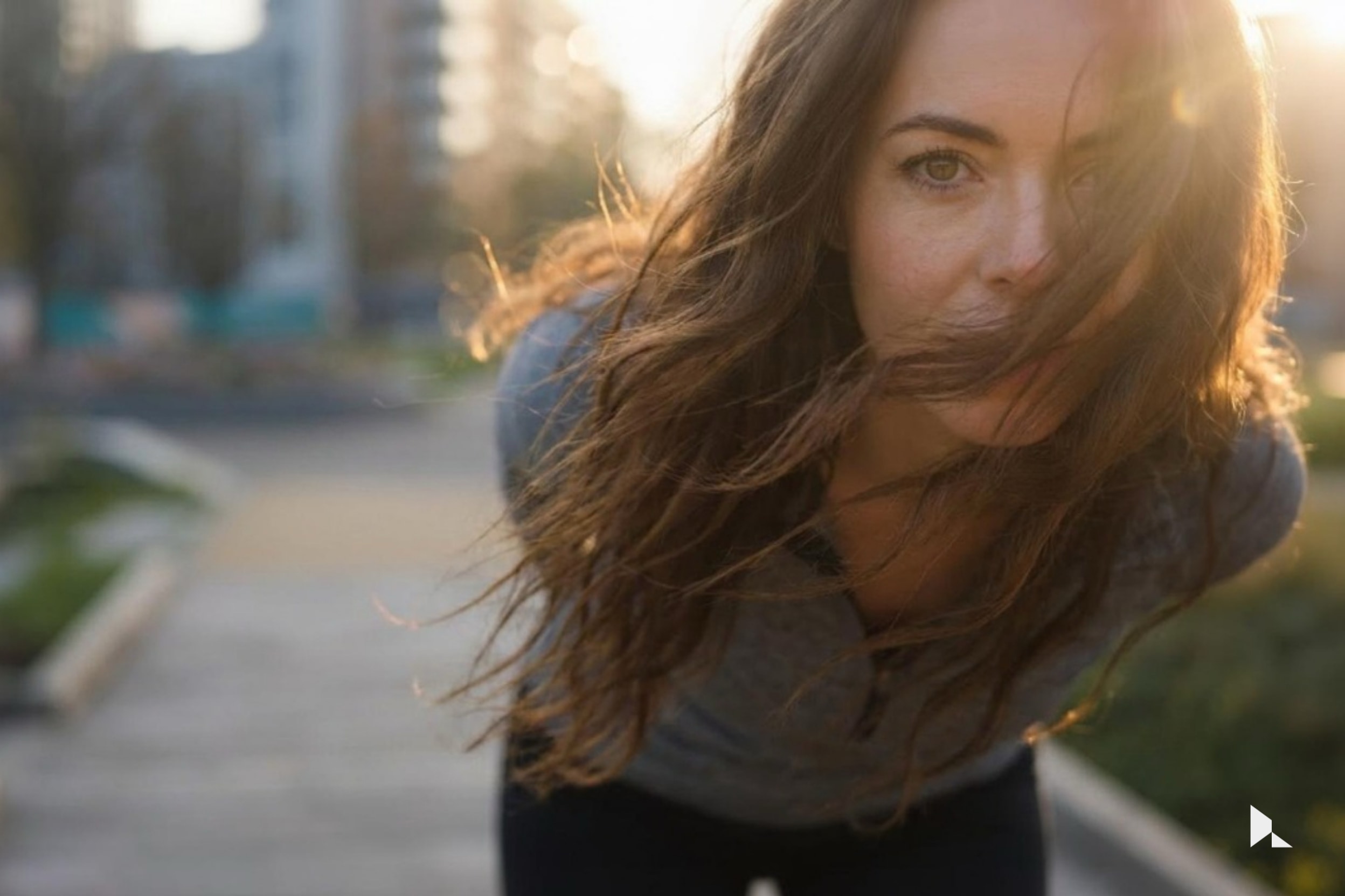 A resident outdoors at Glass Bottle, Dublin, hair caught by the wind with the apartment blocks behind