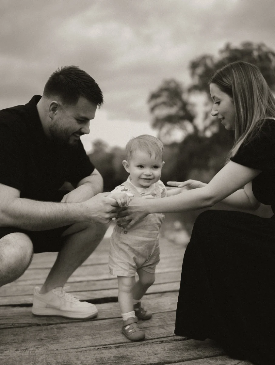 Parents aidant leur petit garçon à se mettre debout sur un  ponton au bord d'un lac en dordogne