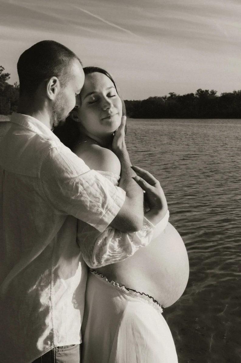 Couple enlacé au bord d'un lac en noir et blanc - Séance maternité Dordogne