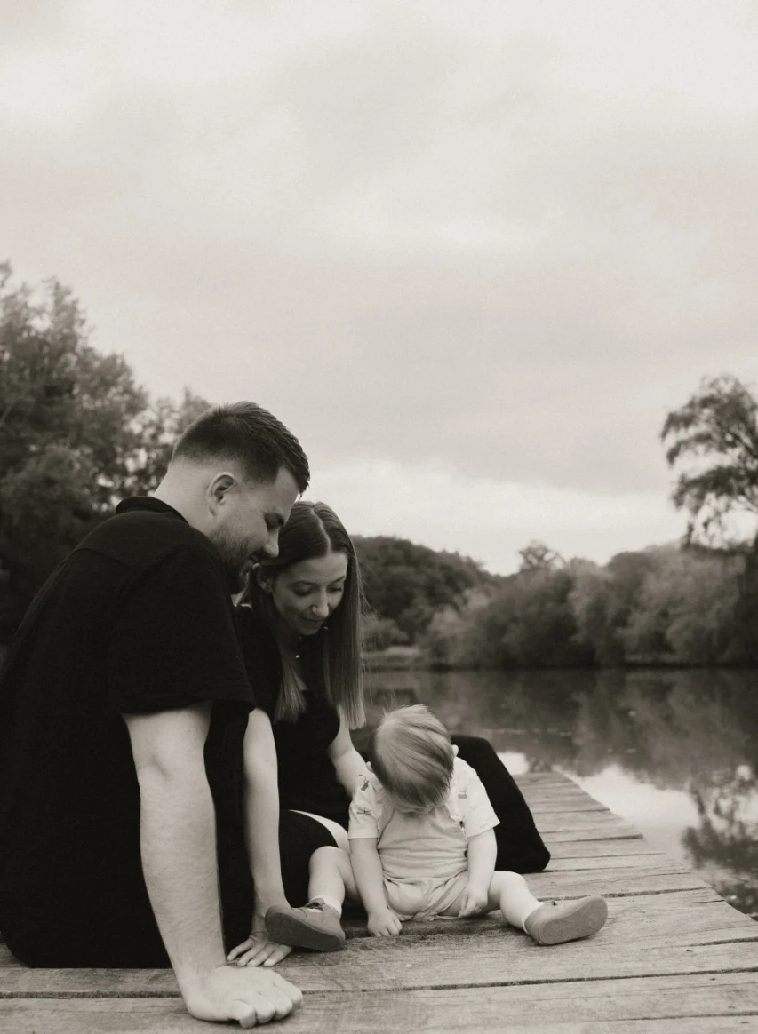 Parents regardant leur enfant jouer au bord d'un lac sur un ponton