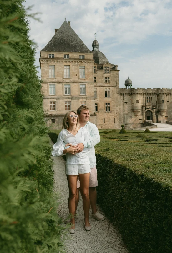 Couple s'enlaçant dans une allée proche d'un chateau 