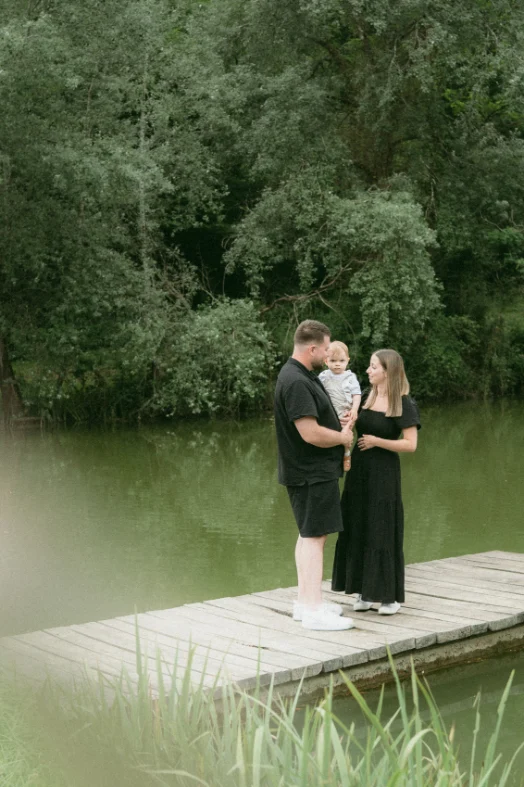 Couple de parent tenant leur petit garçon sur un ponton au bord d'un lac en dordogne