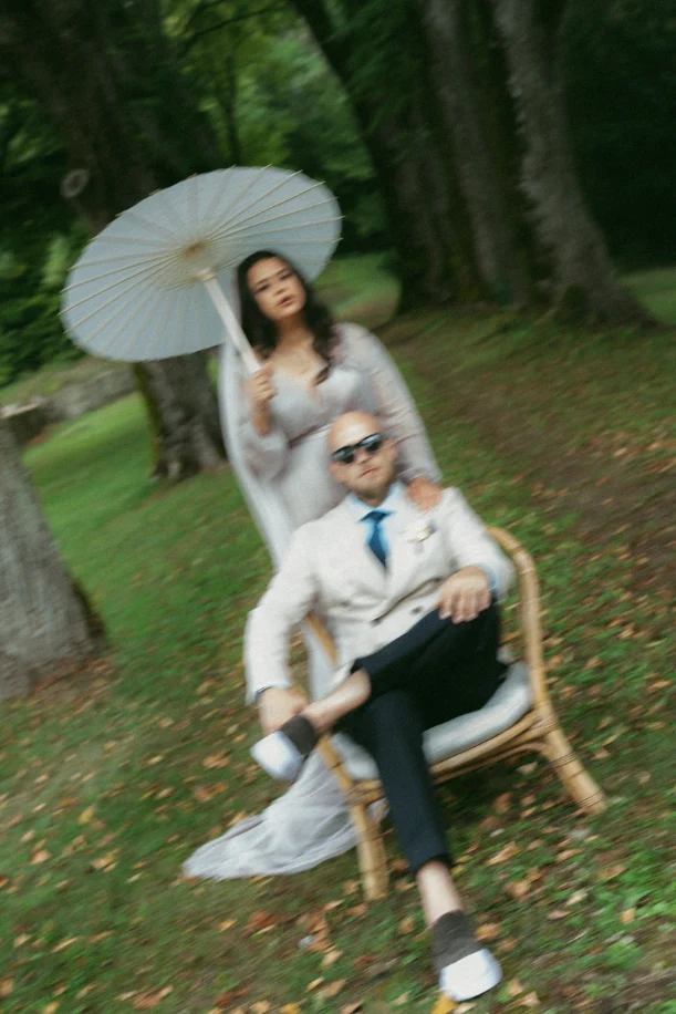 image vintage et floue des mariés dont le mari est assis et la femme et derrière lui et tient une ombrelle