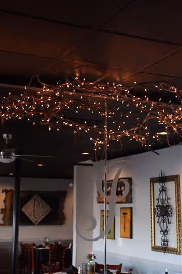Cozy restaurant interior with tables, chairs, wall decorations, and string lights hanging from the ceiling.