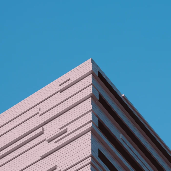 Angular corner view of a modern pink building against a clear blue sky.