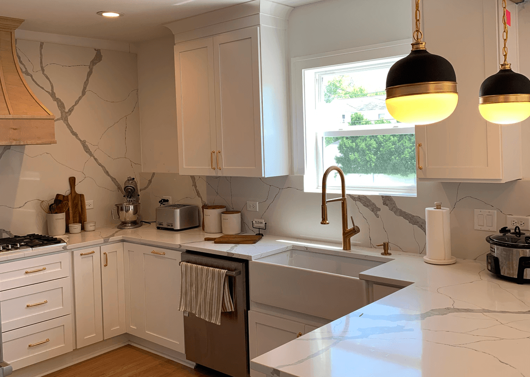 Bright, contemporary kitchen with white cabinets, veined quartz, and gold fixtures.