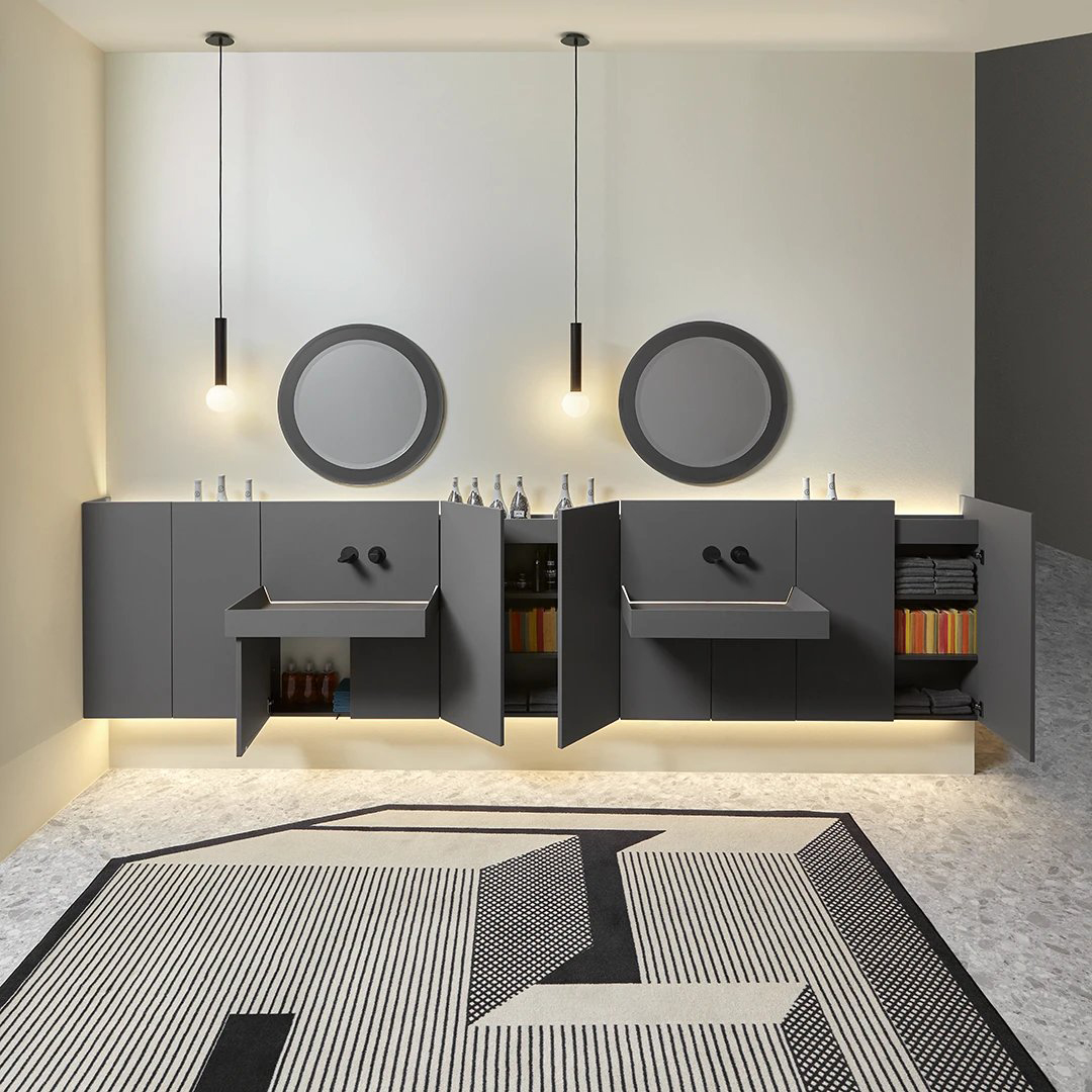 Composition of double washbasin with cabinet, wall-mounted, colour grey, black taps. 2 round mirrors on the wall and lamps wall-mounted under a basin. 3 doors of cabinets open for view of storage interior. Collection Showdown by Antonio Lupi