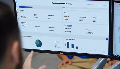 Person viewing computer screen displaying data charts and metrics for equipment overview.