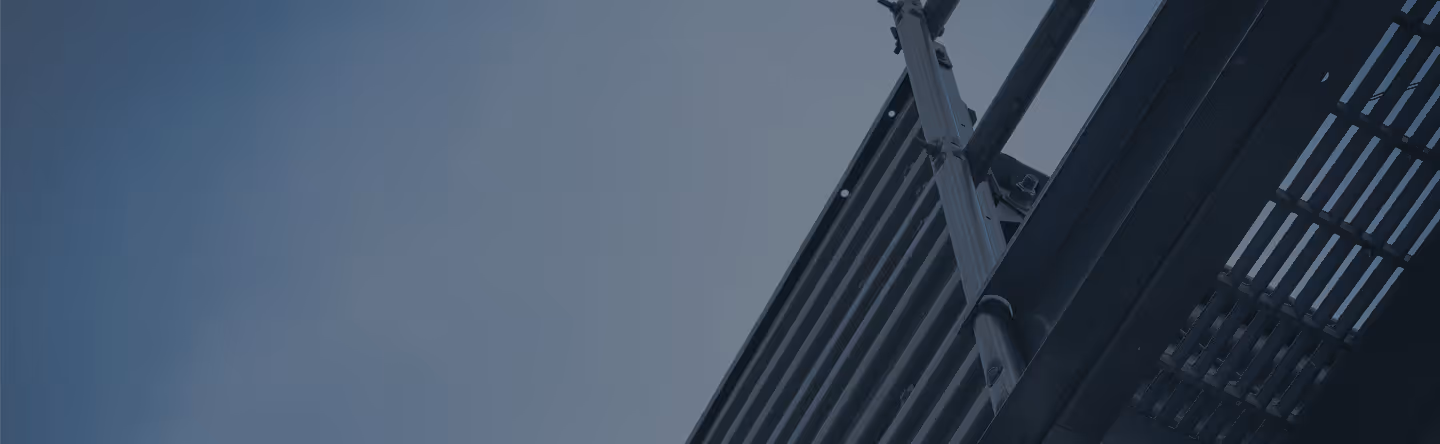 Close-up of metal fire escape stairs and railing against a clear blue sky.