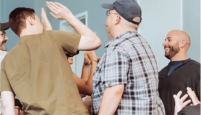 Group of men smiling and giving high fives in a casual indoor setting.