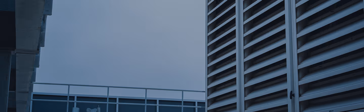 Modern building exterior with metal slats and overcast sky in blue tones.