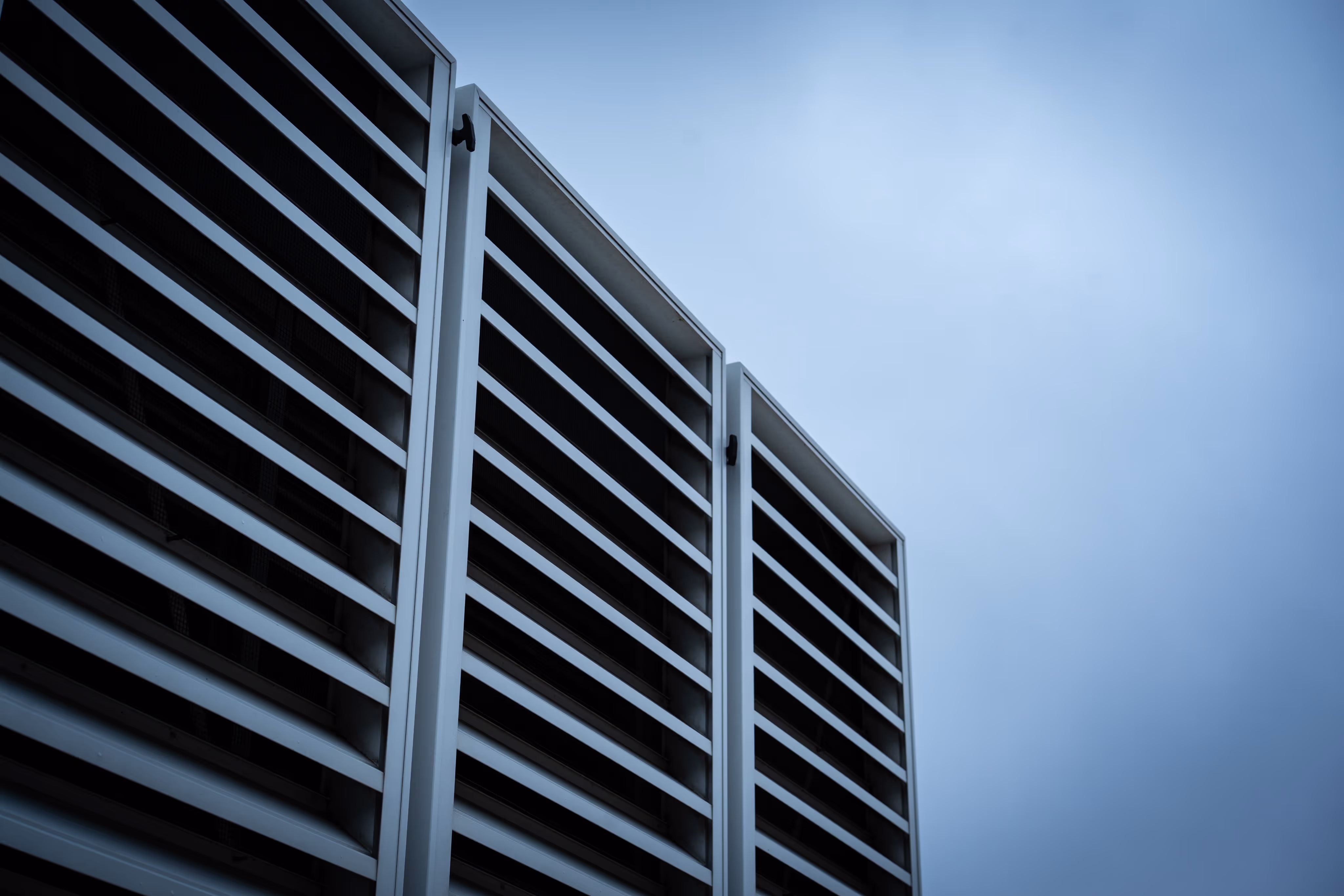 Close-up of a modern building with vertical and horizontal metal slats under a blue sky.
