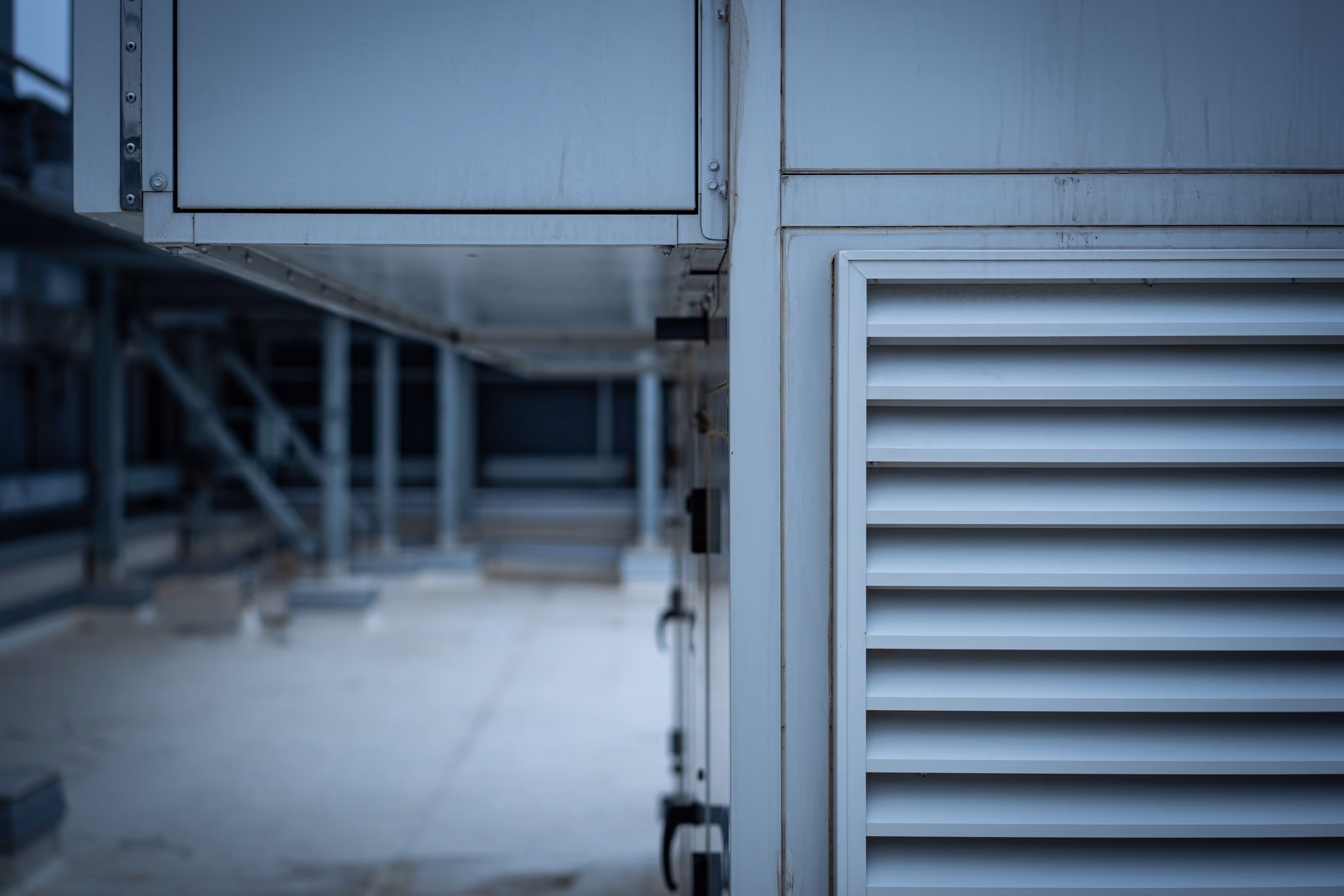 Close-up of metal industrial vents and panels on a rooftop with blurred background.